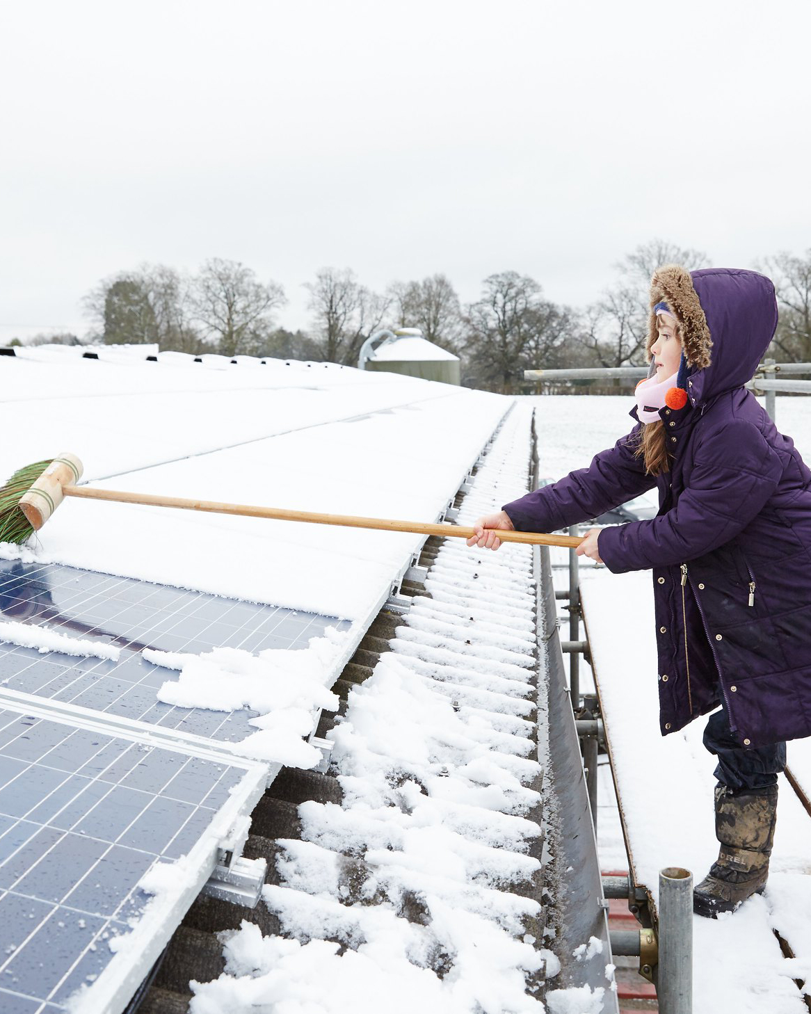 Girl clearing snow off solar panels